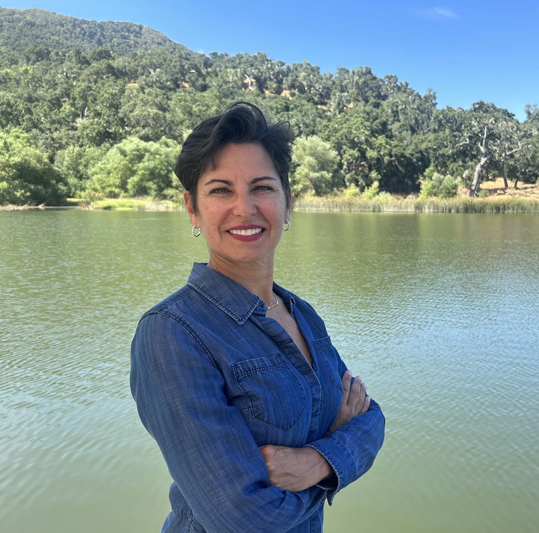 Elizabeth Orona standing beside a lake with the Santa Ynez Valley oak hills behind her